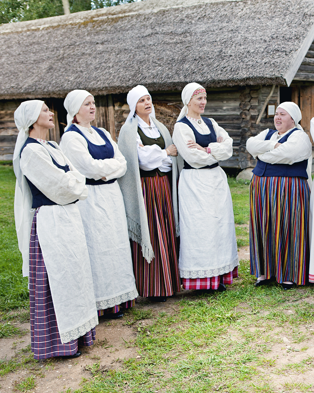 Latvian women are singing in the side by side in their traditional costumes.