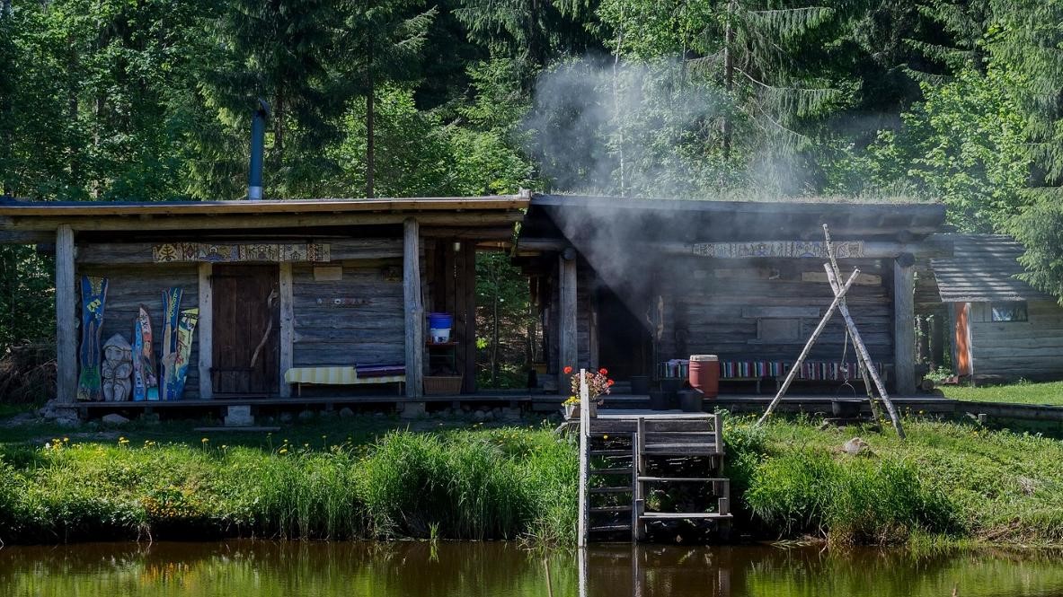 Smoke coming out from sauna, on the summery green lake shore.
