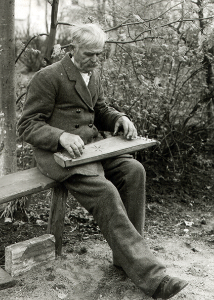 Old man sitting on the bench and  playing Kanklės