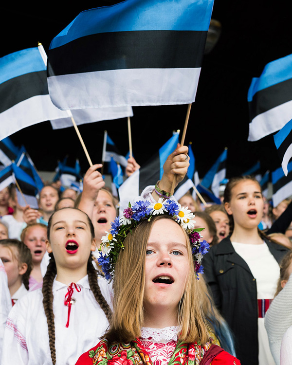 Estonian flags flutter behind the singing girls