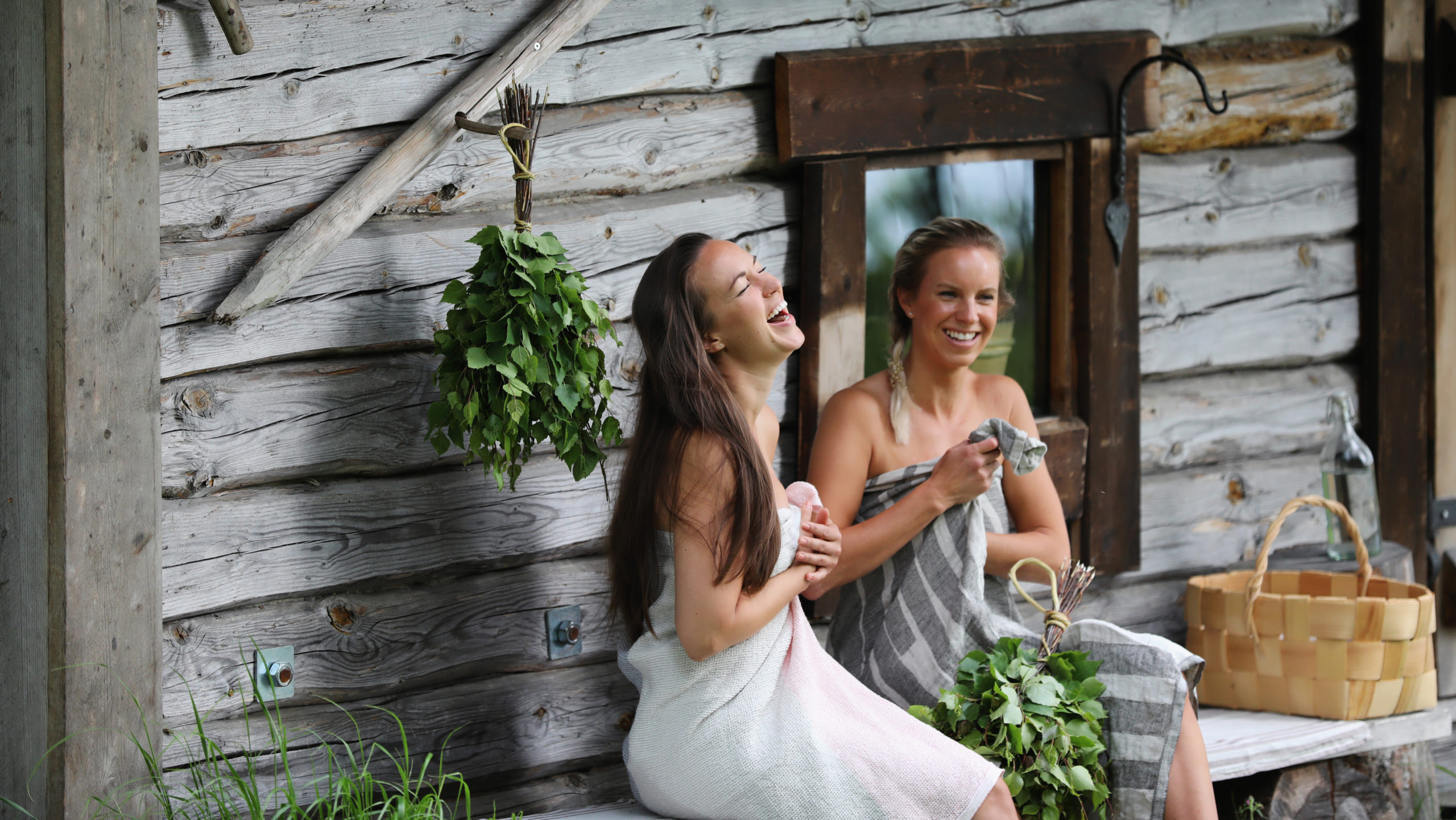 Two young ladies in front of wooden sauna.